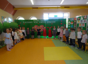Grupa dzieci śpiewa piosenkę w tle dekoracja.
